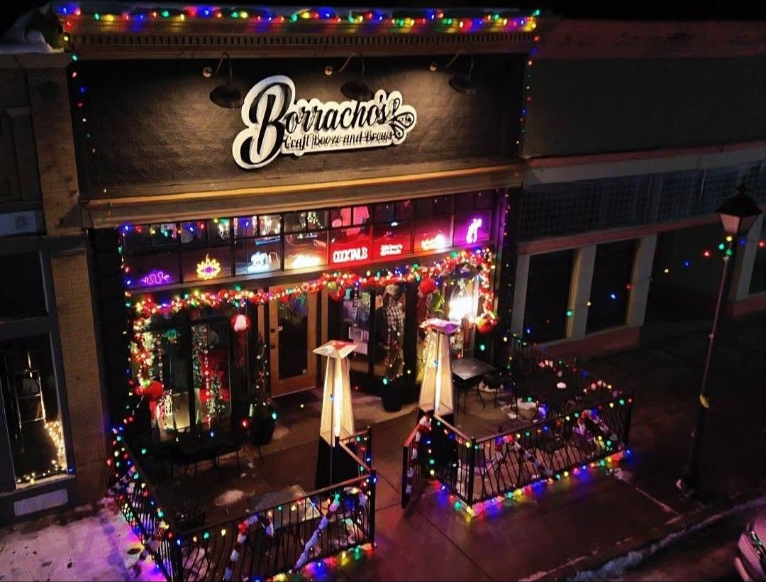 Borracho's storefront on Bridge St lit up with holiday lights at night, patio railings wrapped in lights