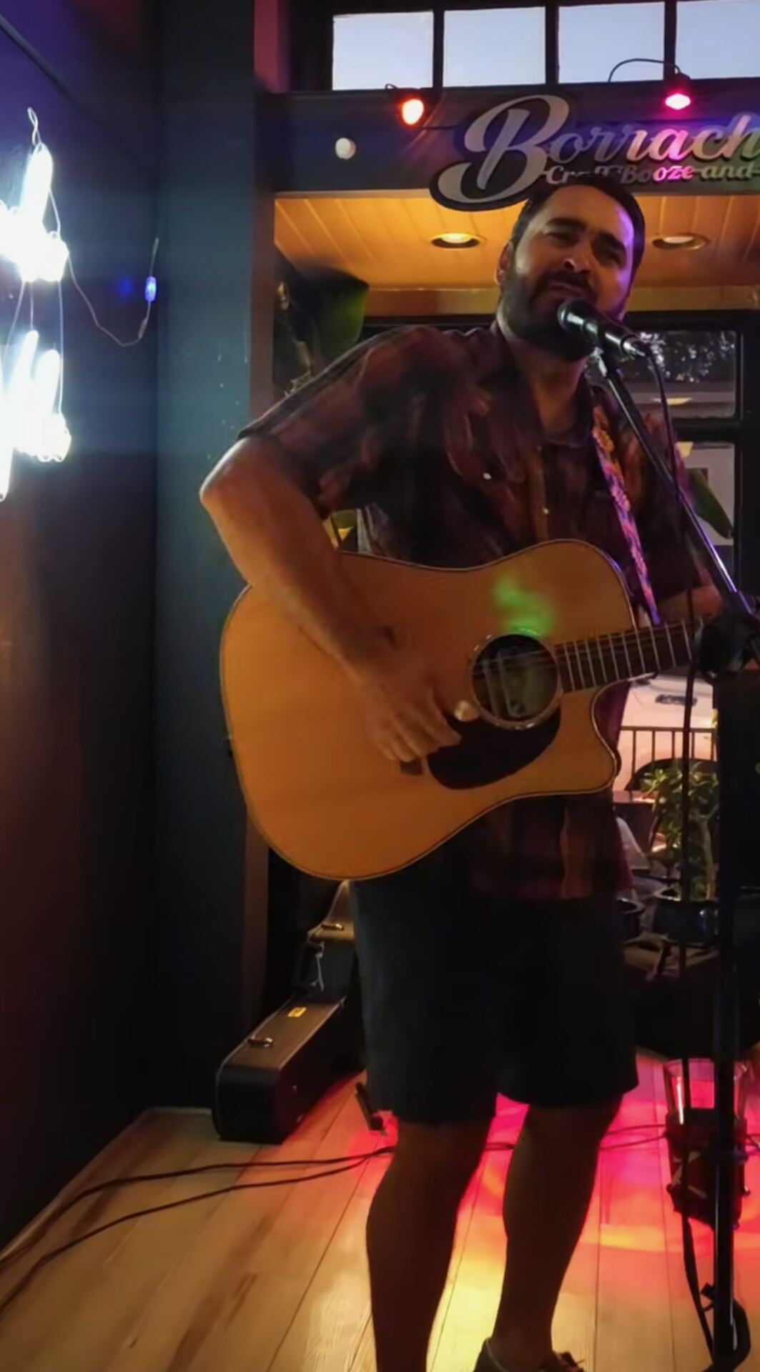 Live musician performing at Borracho's, sign visible behind him